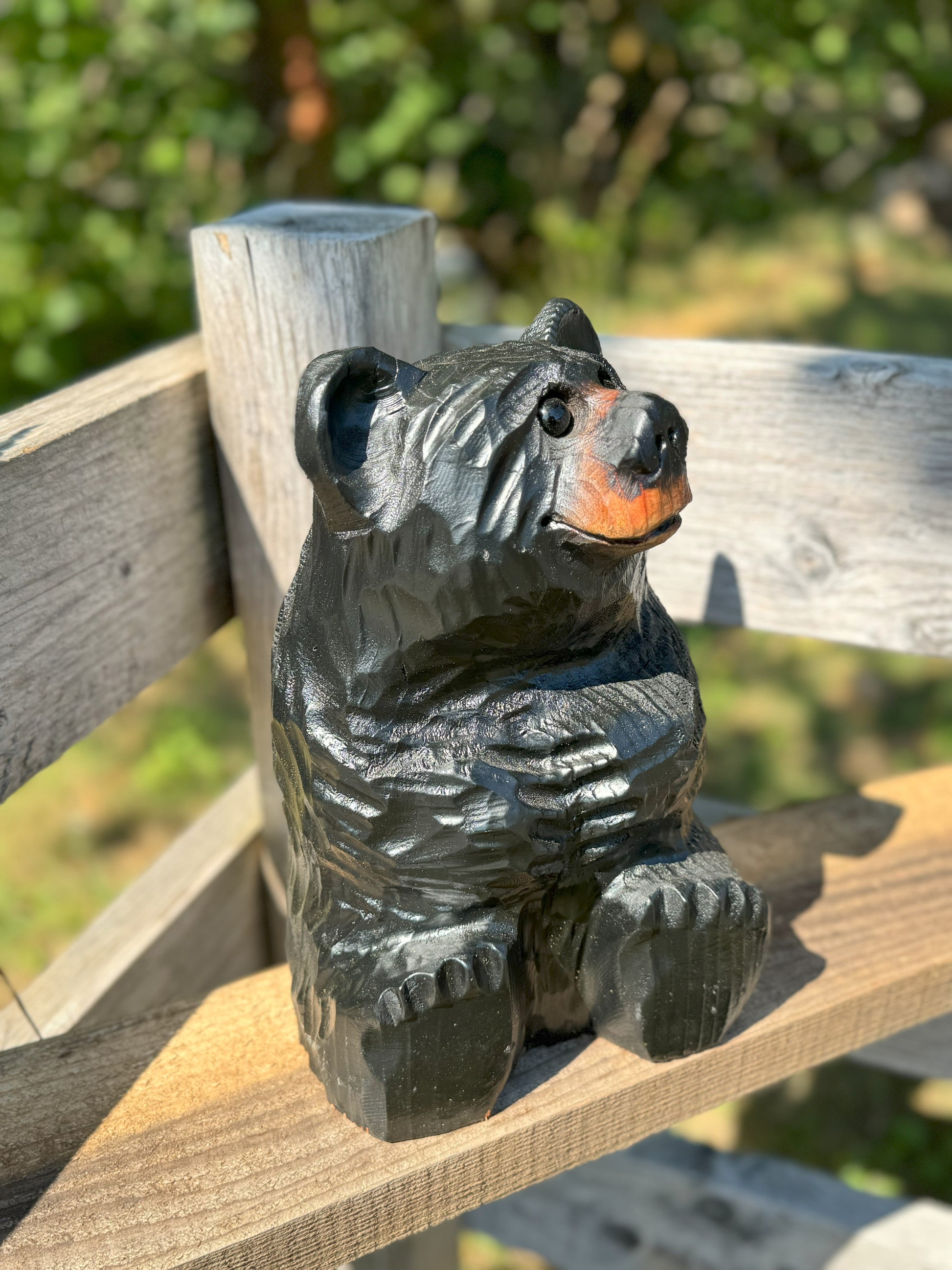 Black bear figurine on a wooden surface with a blurred natural background